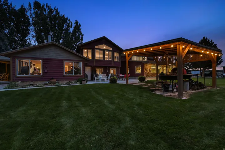 Expansive lawn with a wooden pergola, string lighting, and an outdoor cooking area
