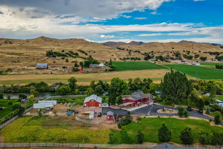 Expansive landscape featuring rolling hills, a winding river, and multiple structures including a residential building and a barn