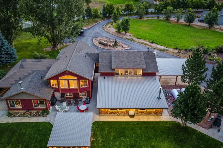 Expansive property featuring multiple structures with complementary rooflines, a paved driveway, and mature landscaping