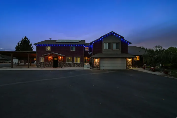 Stone and wood-sided exterior with a two-car garage, covered entry, and a multi-vehicle carport