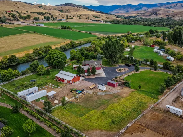 Expansive property featuring a riverfront setting, multiple outbuildings, paved driveways, and surrounding agricultural fields