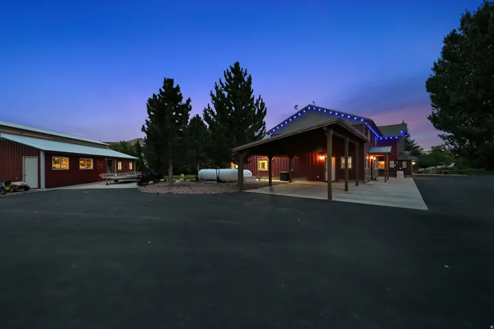 Spacious paved driveway, a large red barn with a metal roof, and an attached carport with wood columns