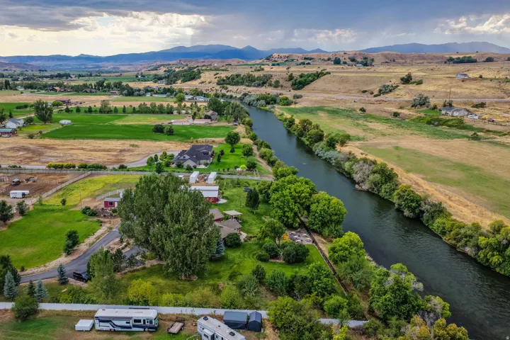 Expansive riverfront property with mature trees, green spaces, and mountainous terrain