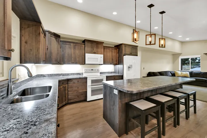 Kitchen featuring wood-finish cabinetry, stone-finish countertops, and a double basin stainless steel sink