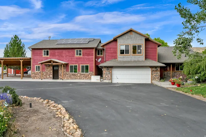 Two-story residence featuring stone and horizontal siding exterior, attached two-car garage, covered entry, and solar panel array
