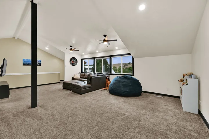 Spacious room featuring vaulted ceilings, recessed lighting, and multiple ceiling fans