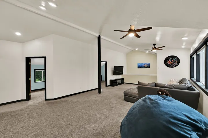 Spacious room with carpet flooring, recessed lighting, vaulted ceilings, and multiple windows