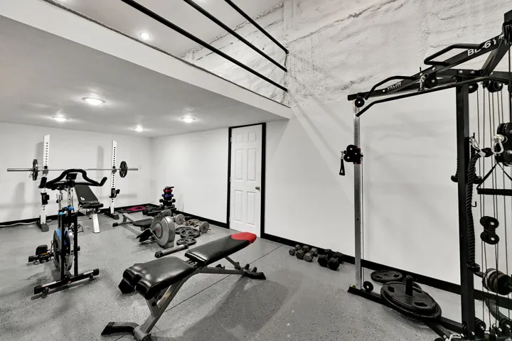 Finished basement space featuring recessed lighting, smooth white walls, white paneled door, and durable flooring