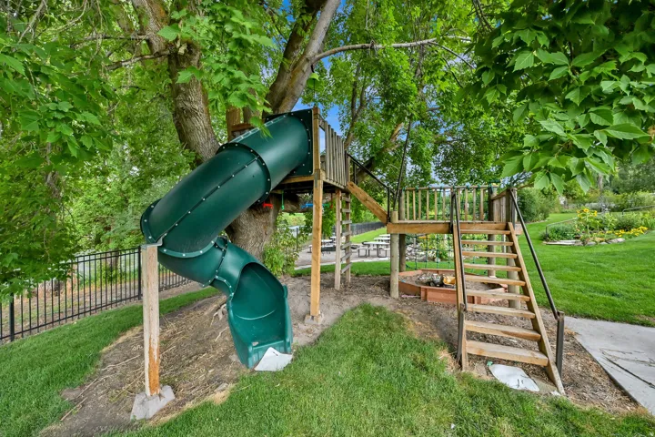 Wood-constructed play structure featuring a spiral slide, elevated platform, and staircase access