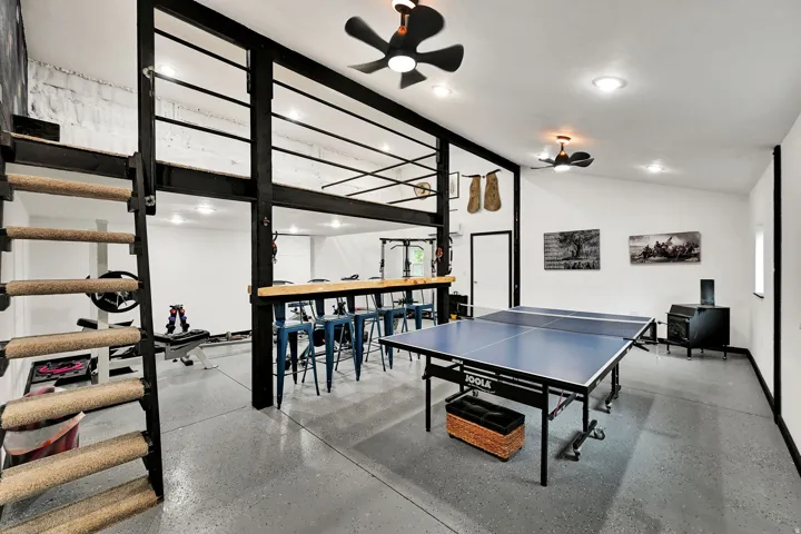 Expansive recreation room featuring a lofted area, exposed structural beams, high ceilings, and recessed lighting