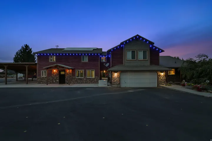 Two-story exterior with stone veneer and wood siding, attached two-car garage, covered entry, and covered carport