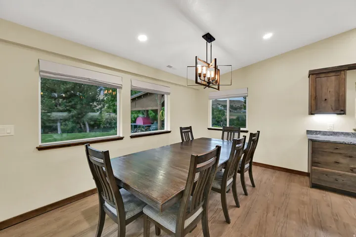 Recessed ceiling lighting, wood-finish flooring, custom wood cabinetry, and a modern rectangular chandelier