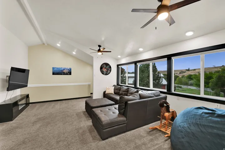 Vaulted ceiling with exposed beams, recessed lighting, and dual ceiling fans