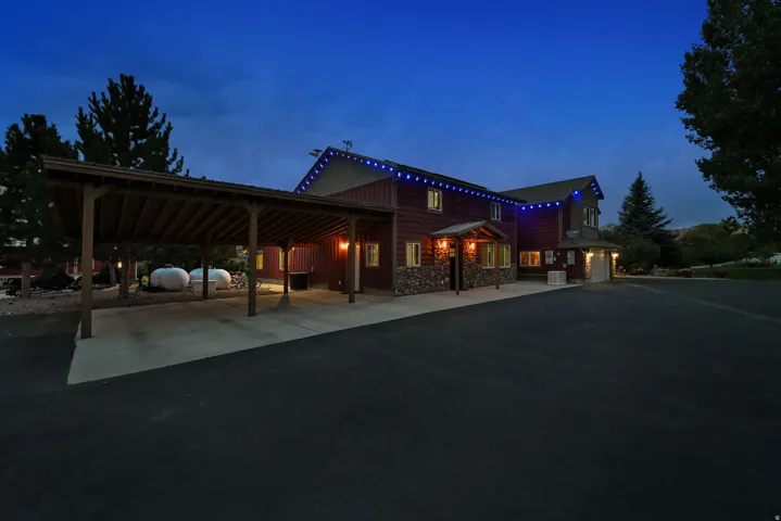 Wood-sided exterior with stone accents, covered carport, and paved driveway