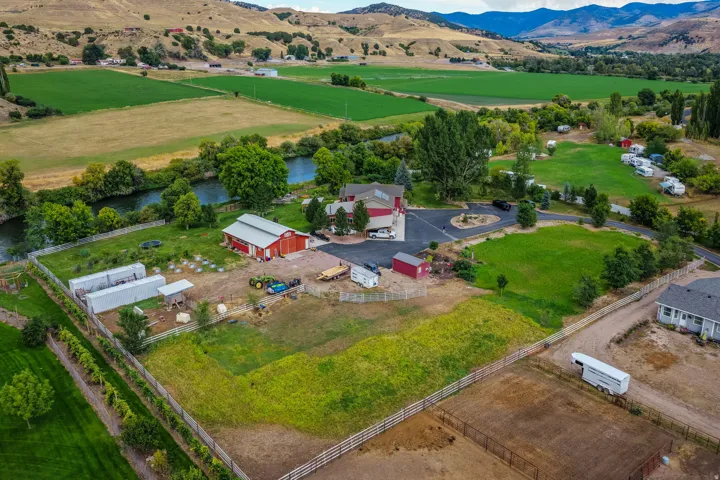 Expansive property featuring a red barn, multiple outbuildings, a circular driveway, and varied terrain with green spaces