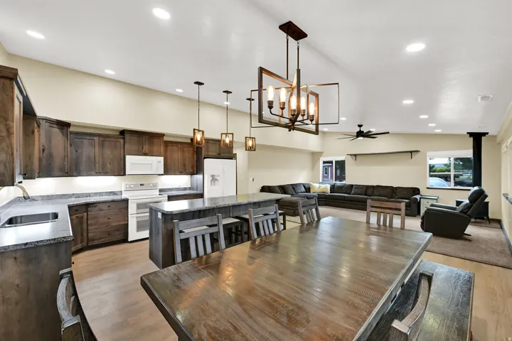 Open-concept living space featuring wood-finish flooring, a kitchen island with seating, dark wood cabinetry, and recessed lighting
