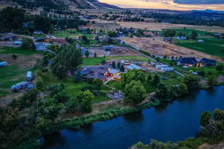 Riverside property with extensive green space, mature trees, and multiple outbuildings