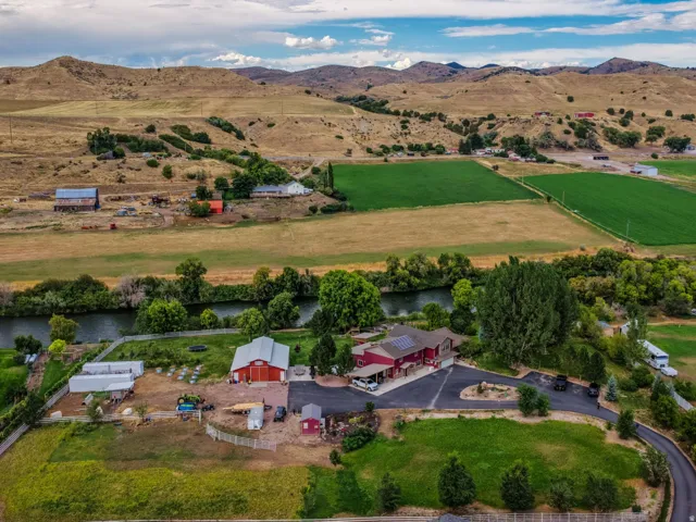 Expansive property with a river, multiple outbuildings, agricultural fields, and mountainous terrain
