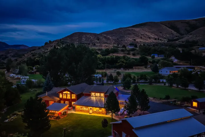 Expansive property featuring multiple structures, mature trees, manicured lawns, and mountain backdrop