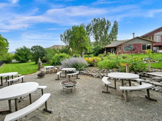 Expansive gravel patio area with multiple picnic tables and two fire pits