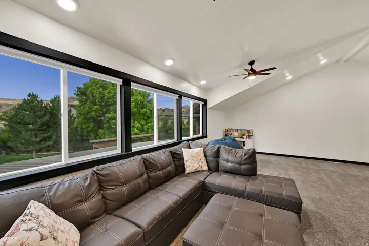 Expansive windows with dark trim, recessed lighting, vaulted ceiling, ceiling fan, and carpeted flooring