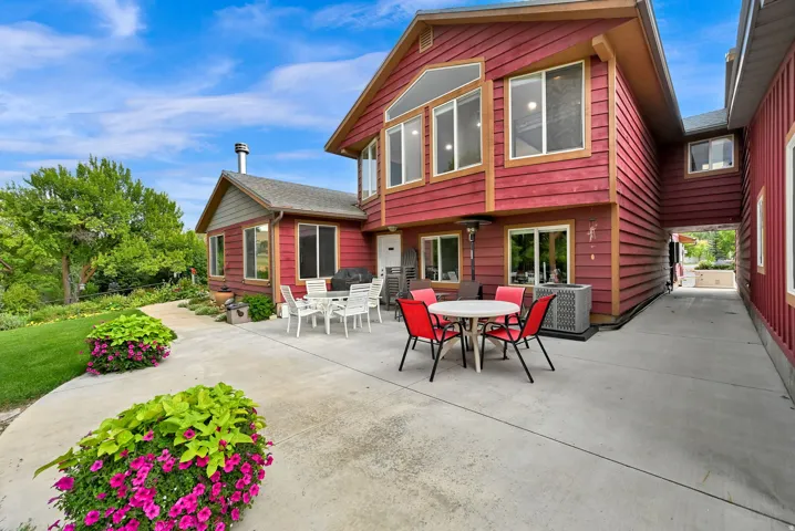 Expansive concrete patio with red siding, multi-pane windows, and an elevated walkway connecting structures