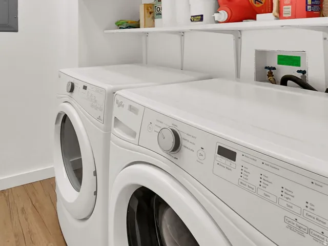 Laundry area featuring wood-finish flooring, built-in shelving, and overhead cabinetry