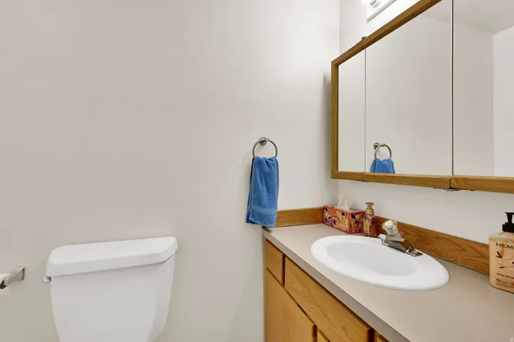 Powder room featuring a built-in vanity with wood-finish cabinetry, a white oval sink, and a framed mirror medicine cabinet