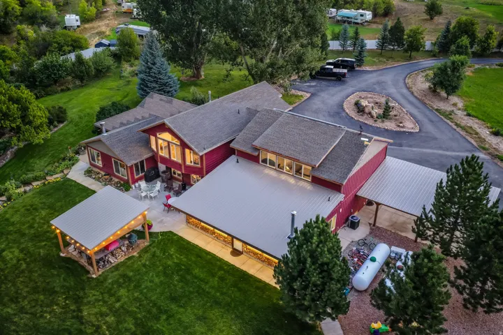 Expansive property featuring a red exterior, multiple rooflines, a paved driveway, and a covered outdoor structure