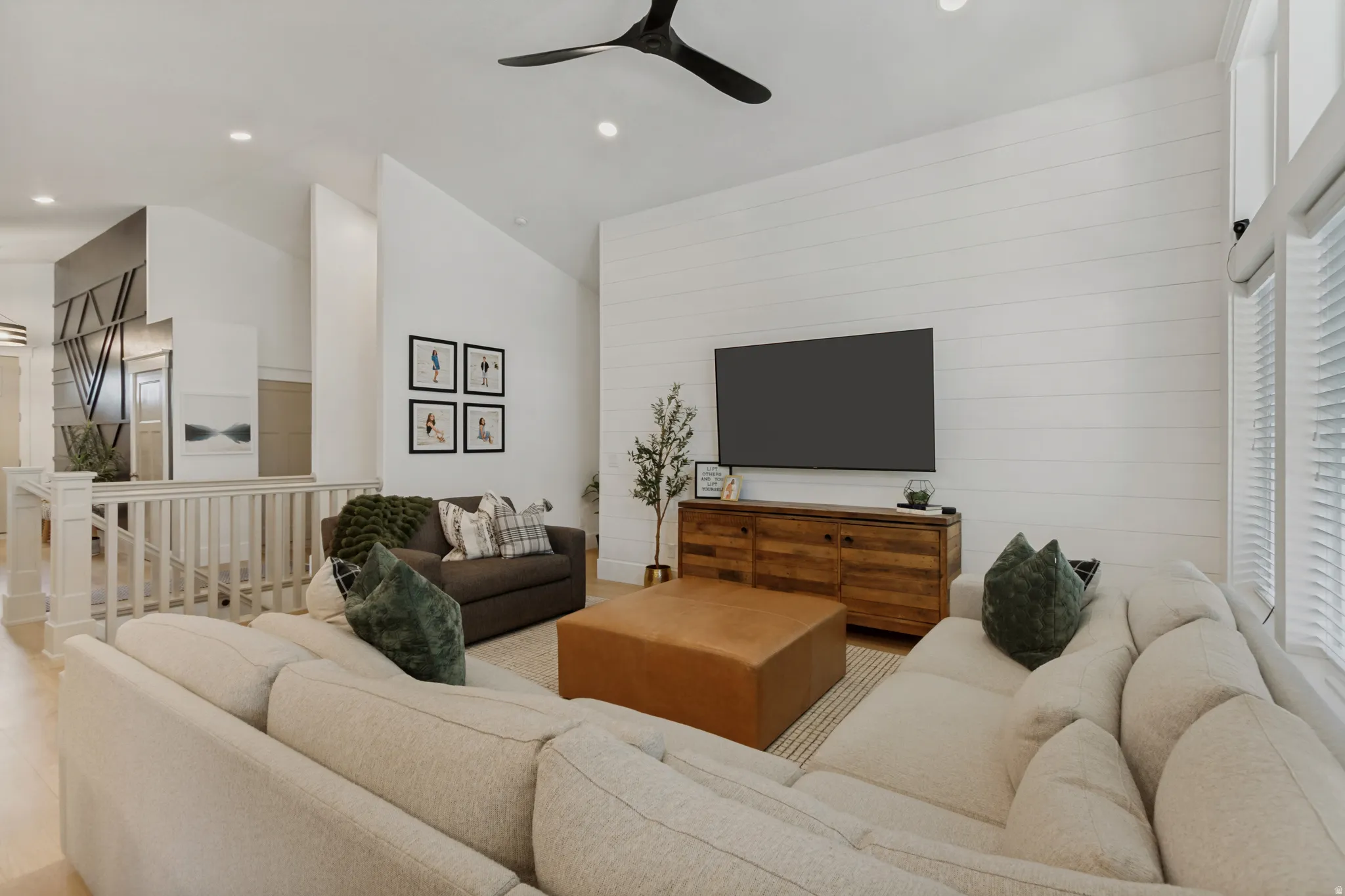 Vaulted ceilings, wood-finish flooring, white shiplap accent wall, recessed lighting, and a modern ceiling fan