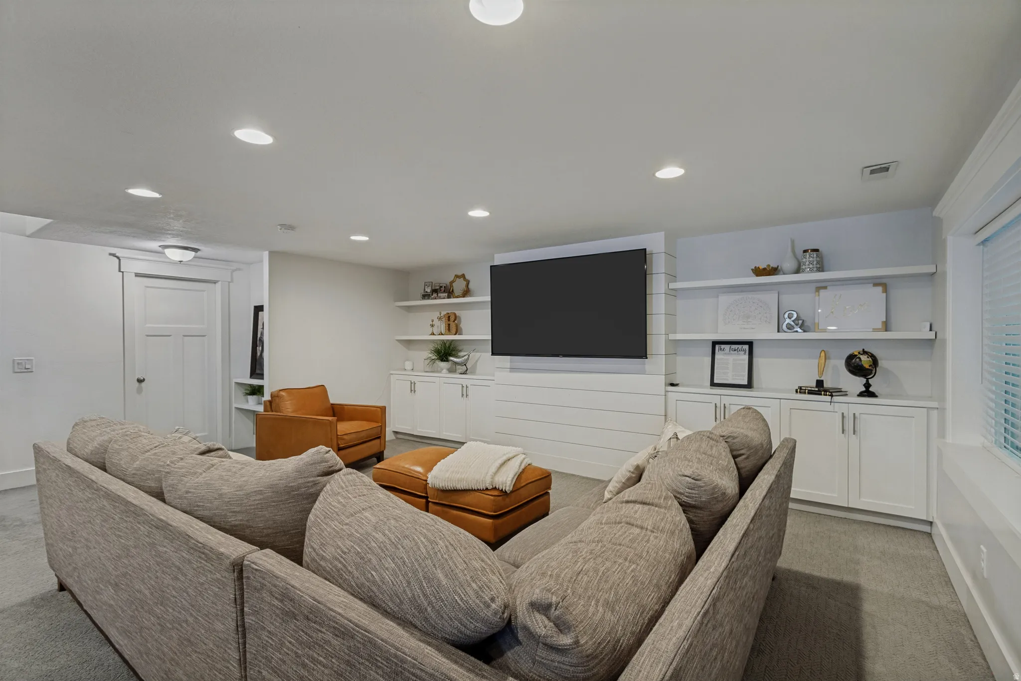 Recessed lighting, built-in shelving, white cabinetry with silver hardware, shiplap accent wall, and wood-finish door