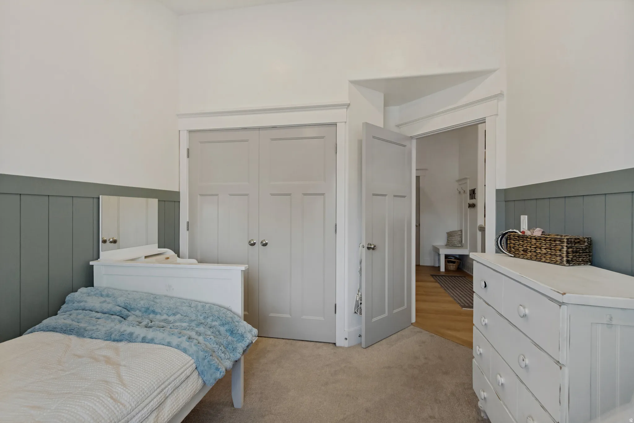 Neutral carpeting, white paneled doors, and wainscoting with a painted finish