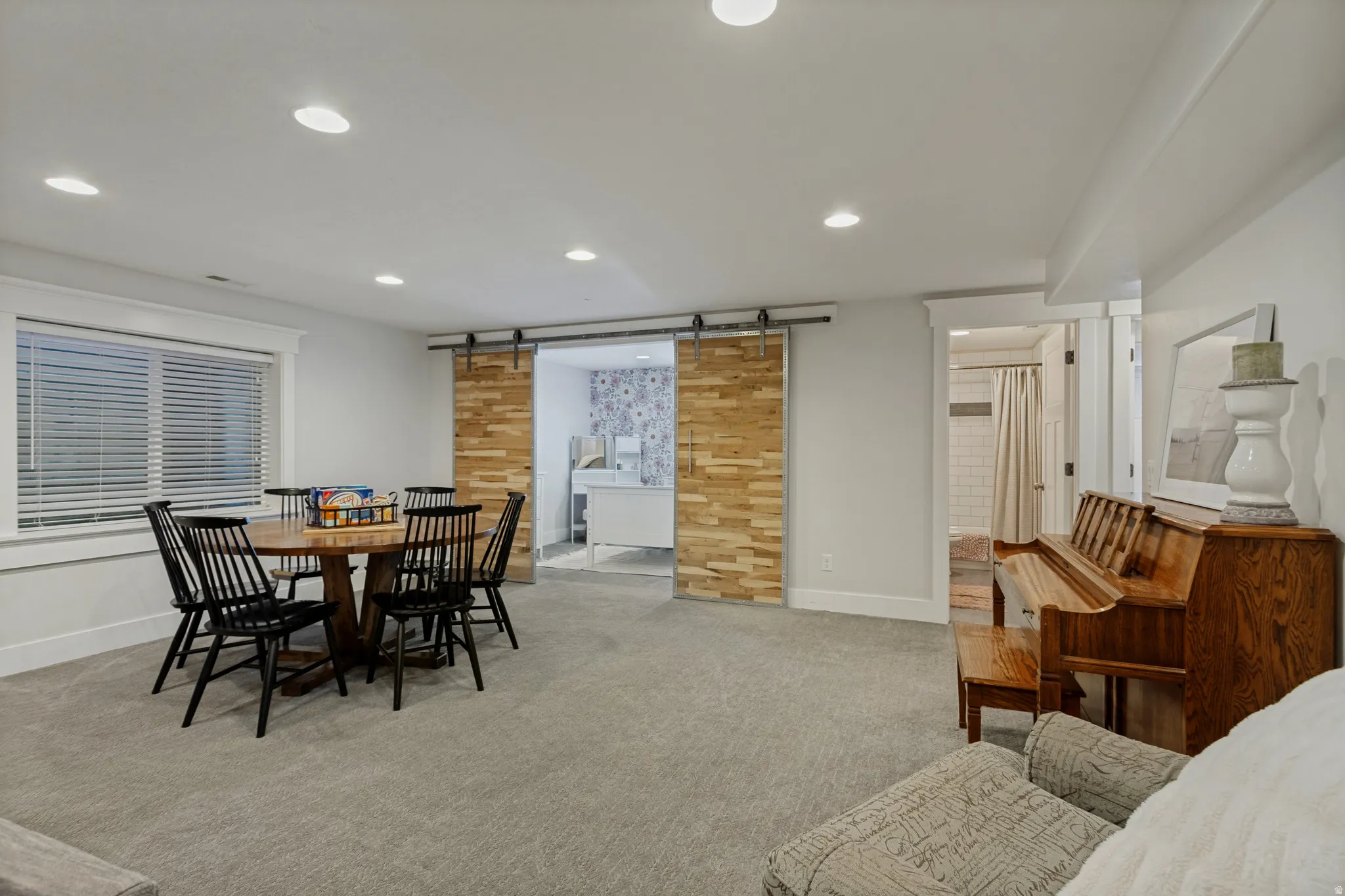 Recessed lighting, wood-finish barn doors, carpeted flooring, and white trim accents