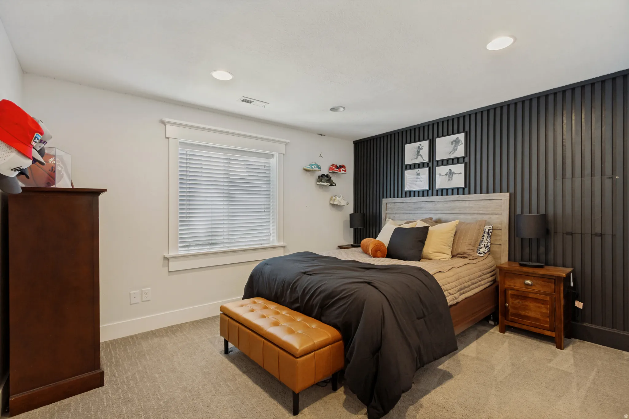 Textured accent wall, recessed lighting, double-paned window with blinds, light-toned carpeting, and white trim