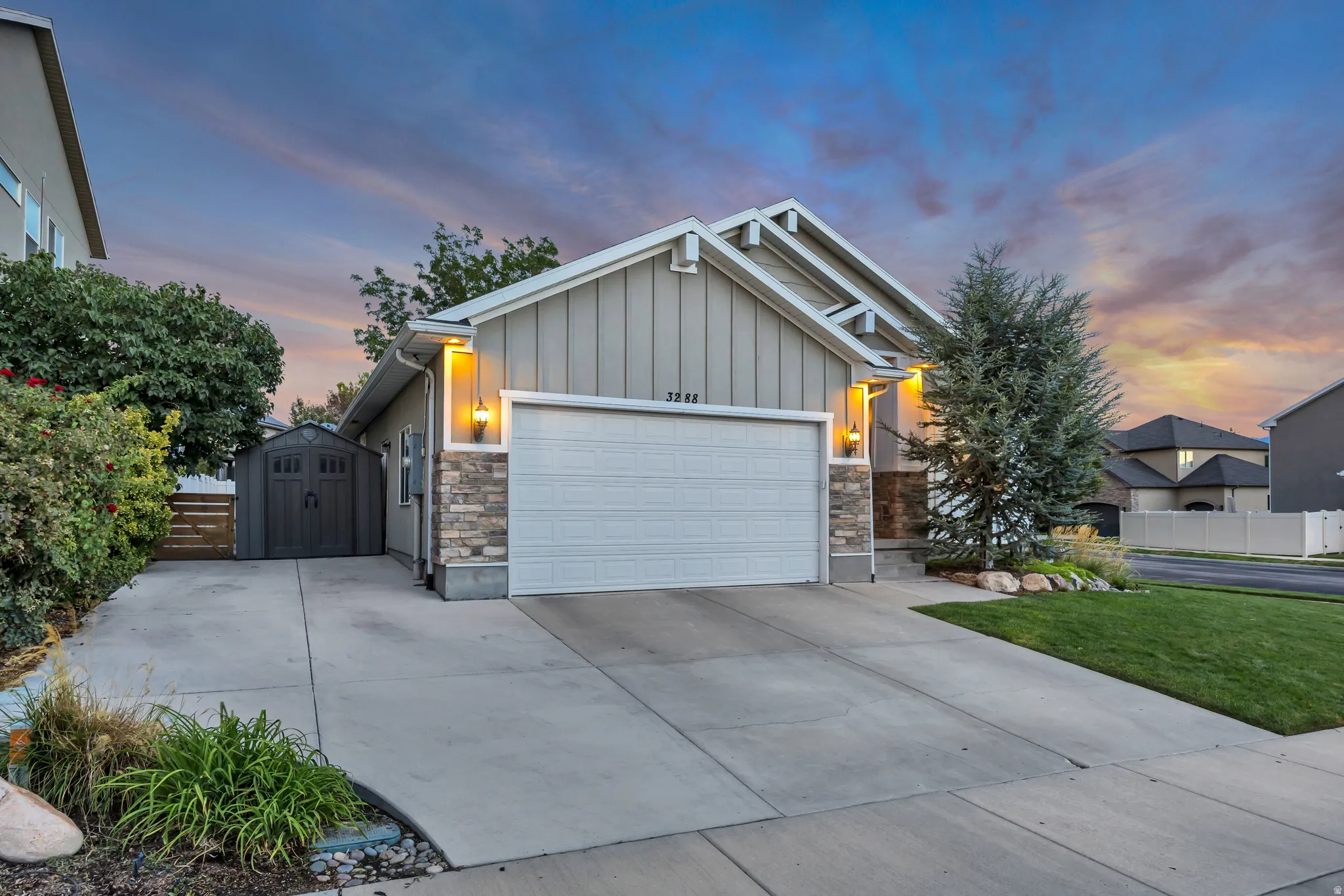 Concrete driveway with an integrated shed, stone veneer accents, and a two-car garage