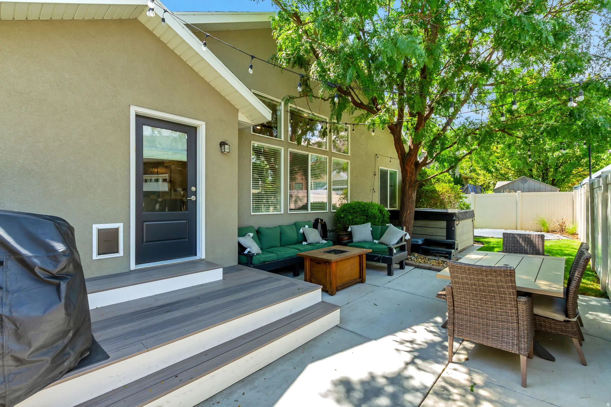 Spacious concrete patio with a composite deck, stucco exterior, and multi-pane windows