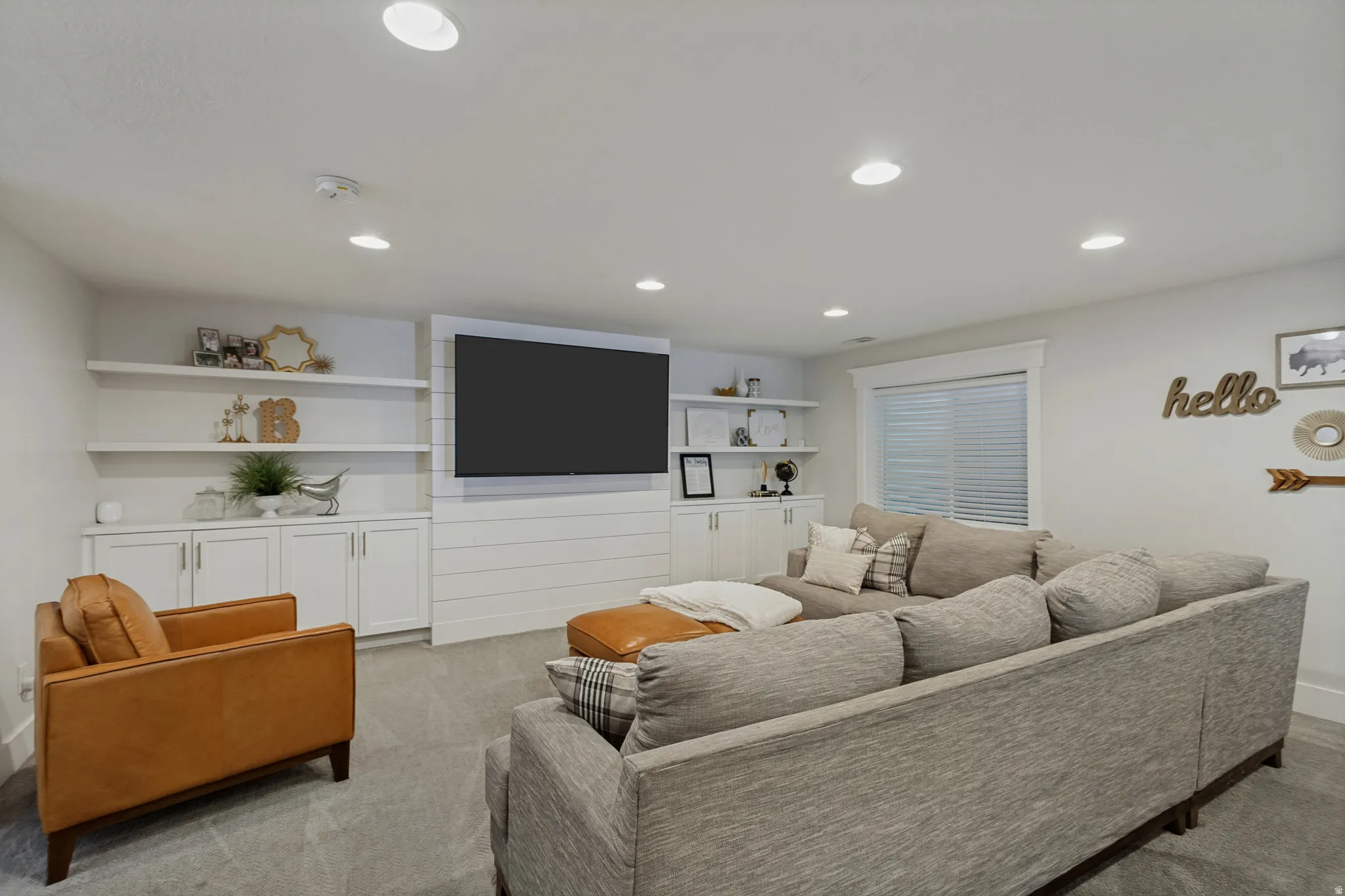 Built-in wall cabinetry with open shelving, recessed lighting, and a window with blinds