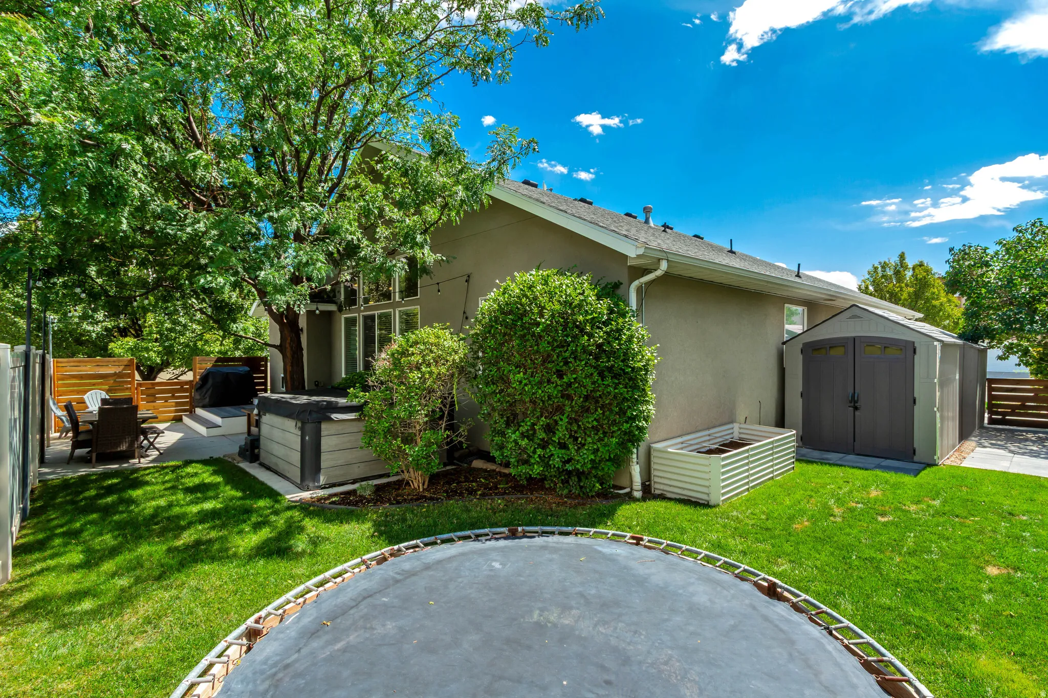 Expansive yard with mature trees, a private patio, and a storage shed