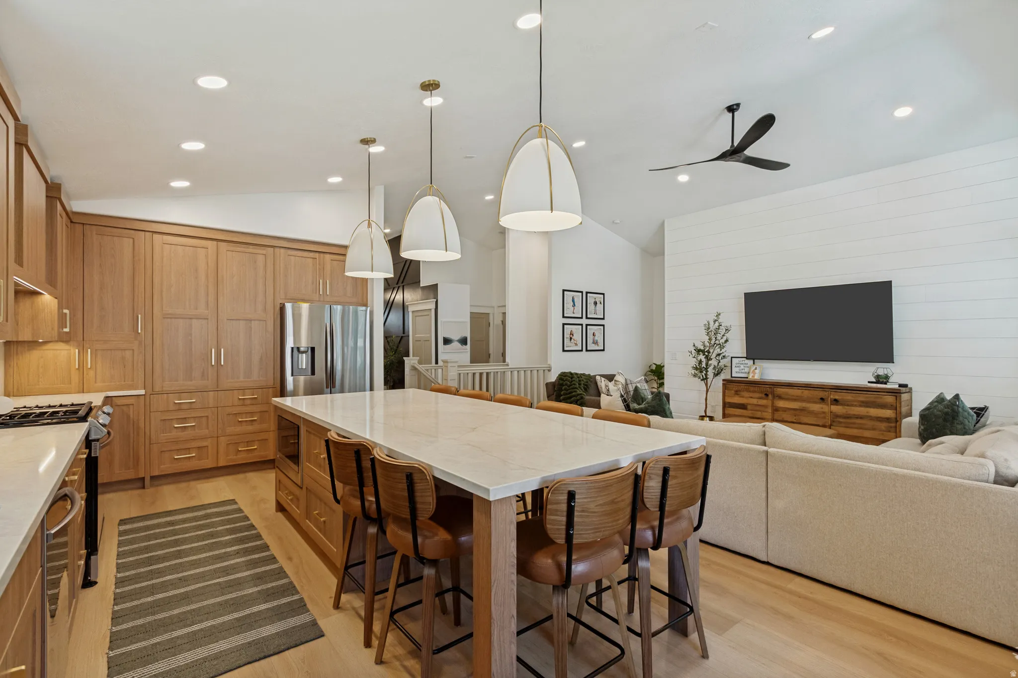Kitchen featuring light wood cabinetry, a large center island with seating, and stainless steel appliances
