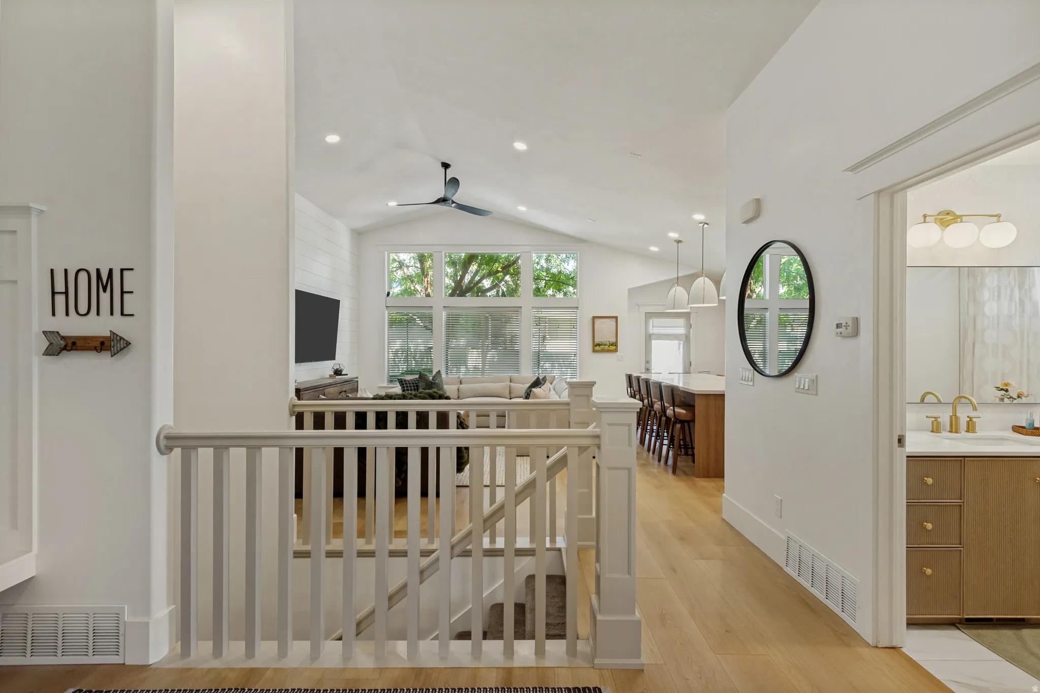 Open-concept living space with vaulted ceilings, recessed lighting, wood-finish flooring, and a contemporary ceiling fan