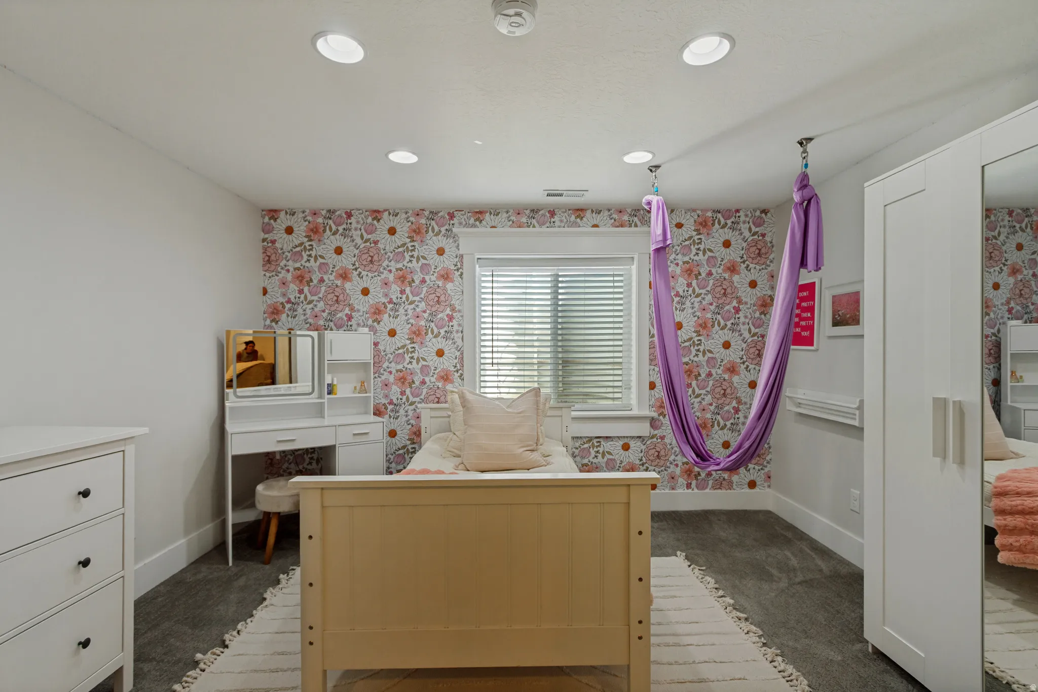 Recessed ceiling lighting, patterned accent wall, window with blinds, and durable carpet flooring