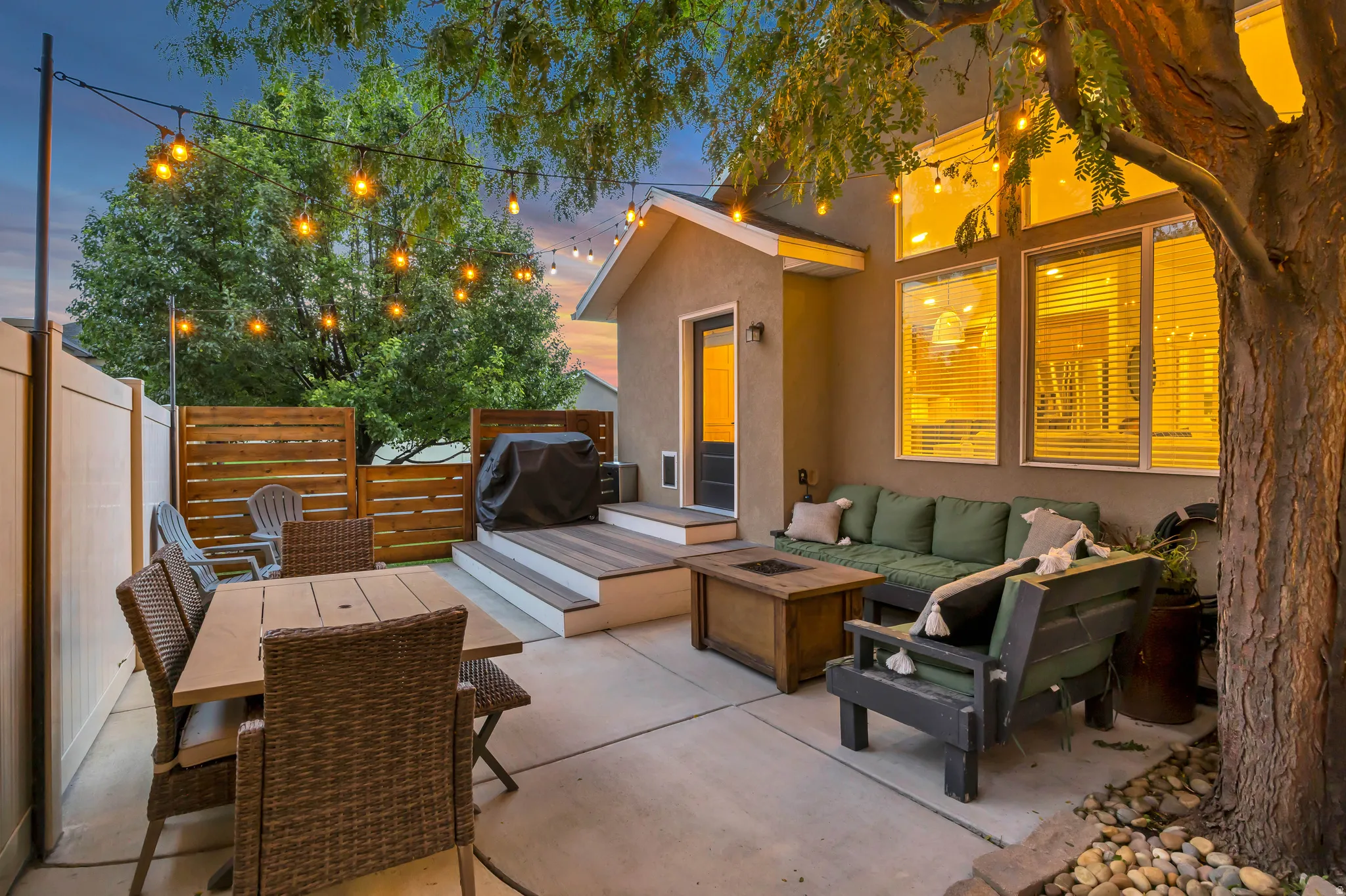 Concrete patio with a wood-finish tiered deck, wood slat fencing, and privacy fencing