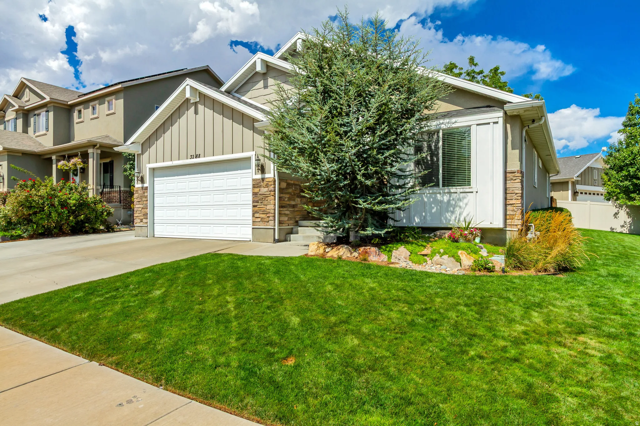 Exterior featuring a stone and siding facade, attached garage, concrete driveway, and front landscaping