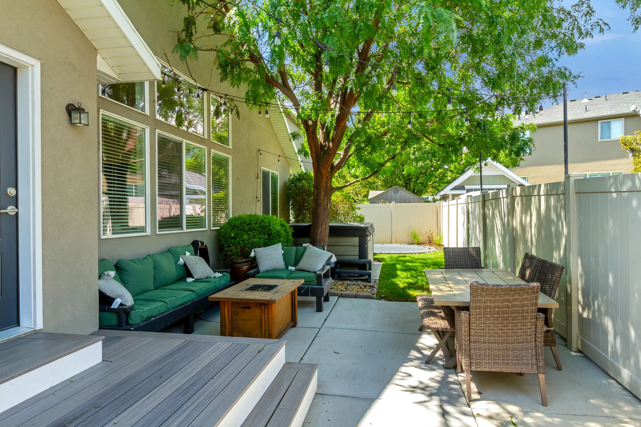 Outdoor patio with wood-finish decking, concrete slab, and a privacy fence