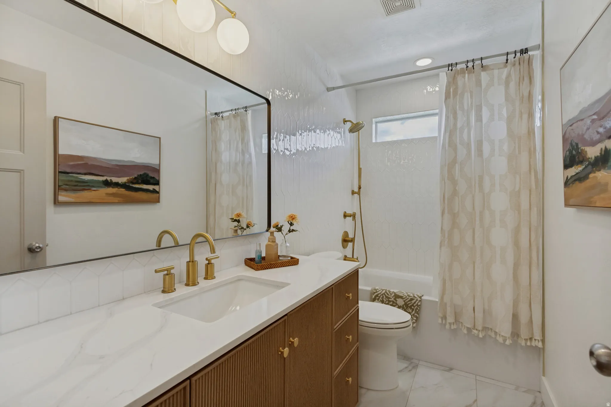 Bathroom featuring a single vanity with wood-finish cabinetry, a white countertop, and gold-finish fixtures