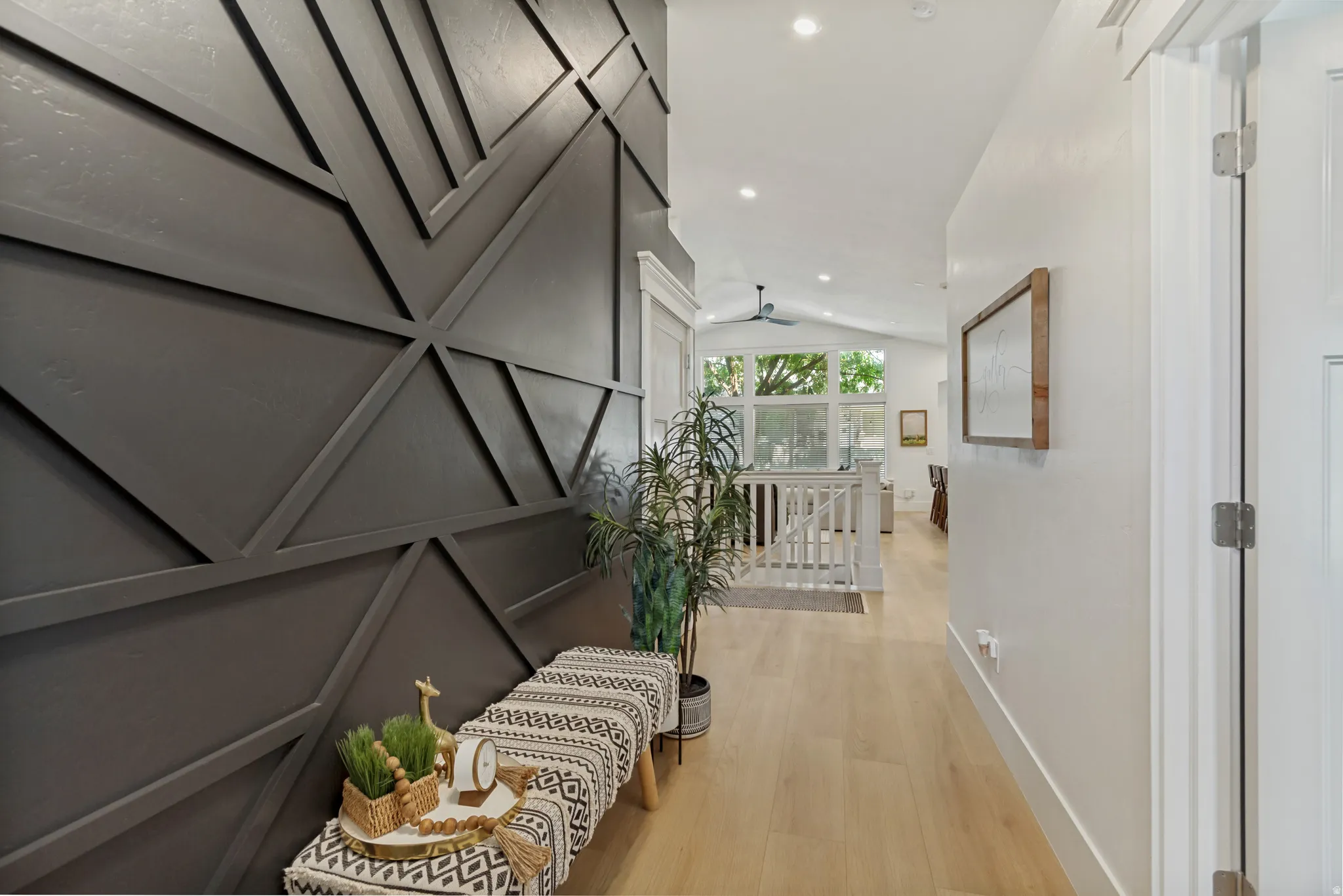 Accent wall featuring geometric paneling, recessed lighting, wood-finish flooring, and a vaulted ceiling