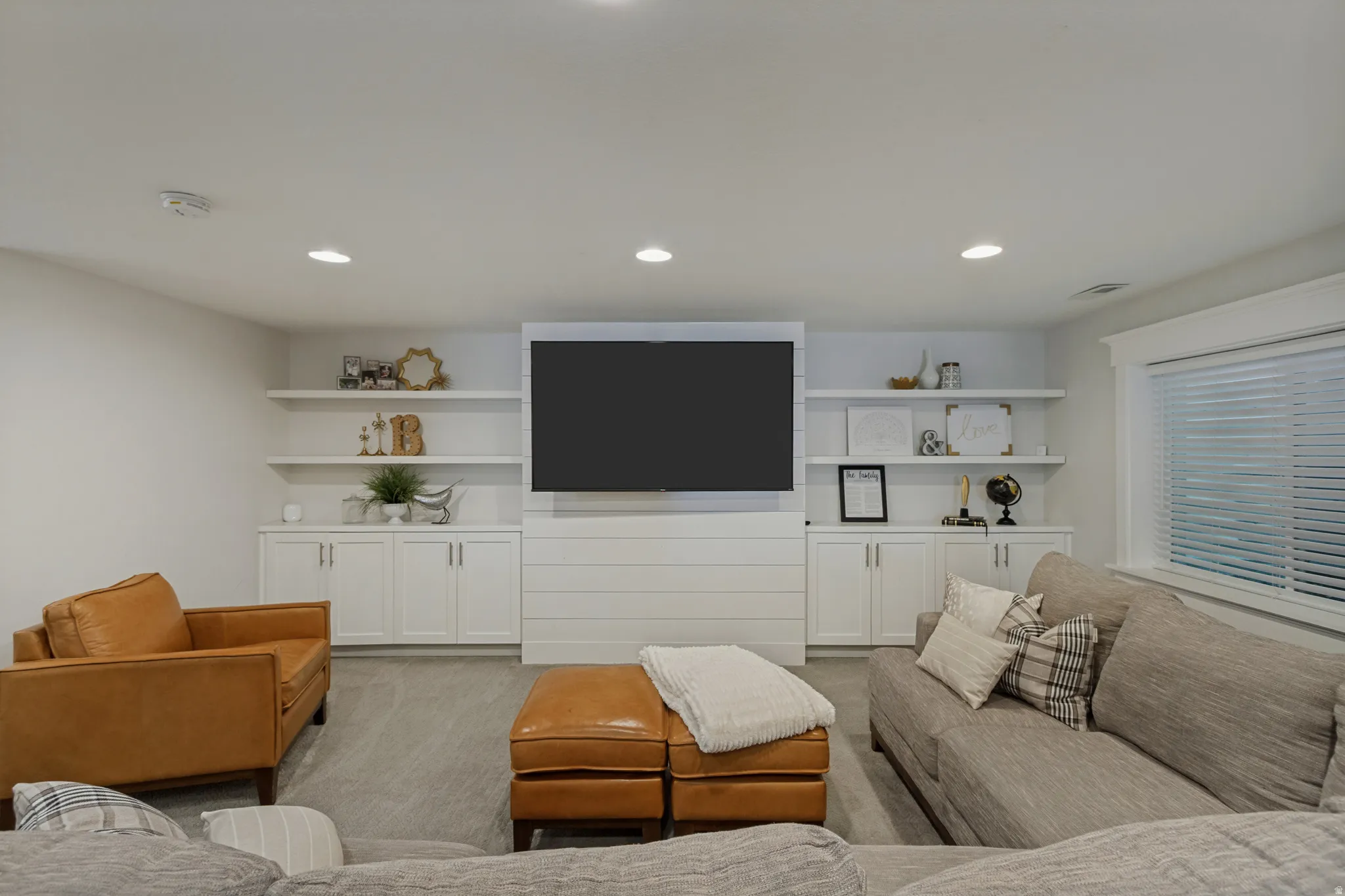 Recessed lighting, built-in shelving, lower cabinetry, shiplap-style wall feature, and a window with blinds