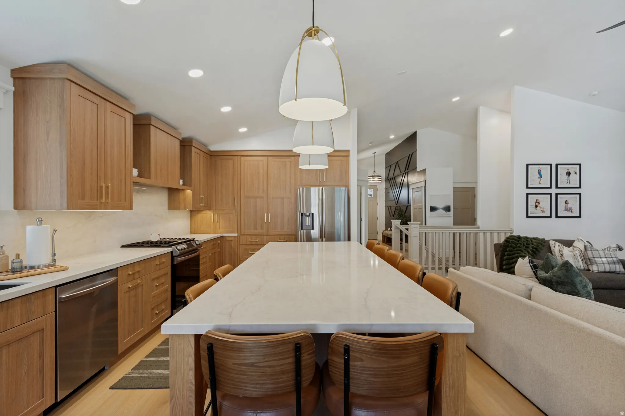 Open-concept kitchen featuring light wood cabinetry, stainless steel appliances, a gas range, and a large central island with seating