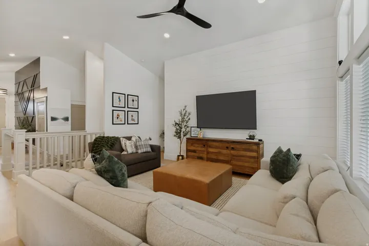 Vaulted ceilings, wood-finish flooring, white shiplap accent wall, recessed lighting, and a modern ceiling fan