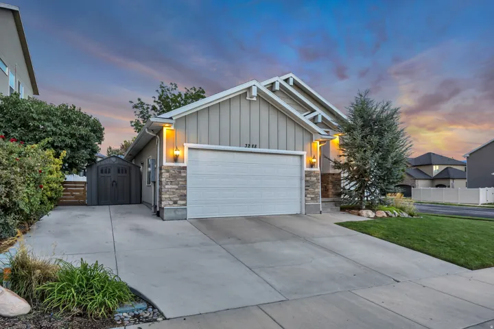 Concrete driveway with an integrated shed, stone veneer accents, and a two-car garage